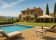 villa in toscana con piscina, sdraio e tavolino con bottiglia e due bicchieri